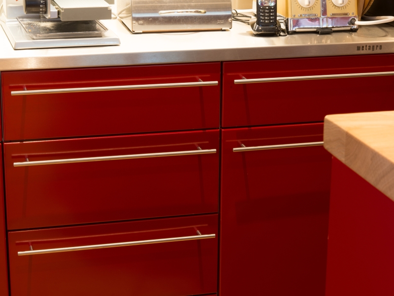 Detail-Aufnahme von Edelstahlküche mit roter Pulverbeschichtung und naturbelassenr Edelstahlabdeckung