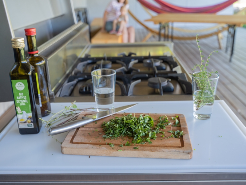 Detail-Aufnahme von geschnittenen grünen Kräutern auf integriertem Schneidbrett (Outdoorküche)