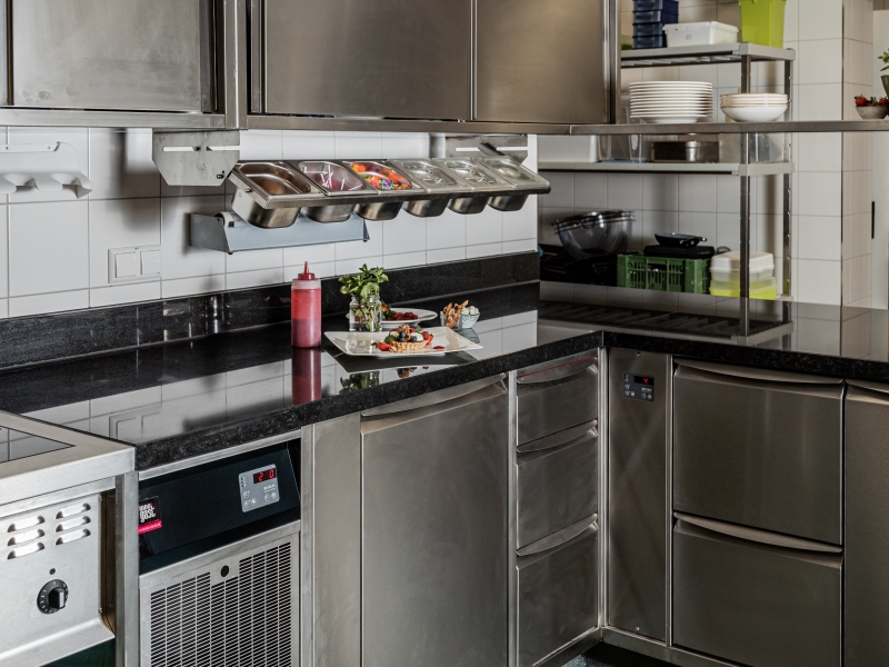 Patisserie über Eck mit dunklem Granit als Arbeitsplatte und GN-Kühlung im Unterbau