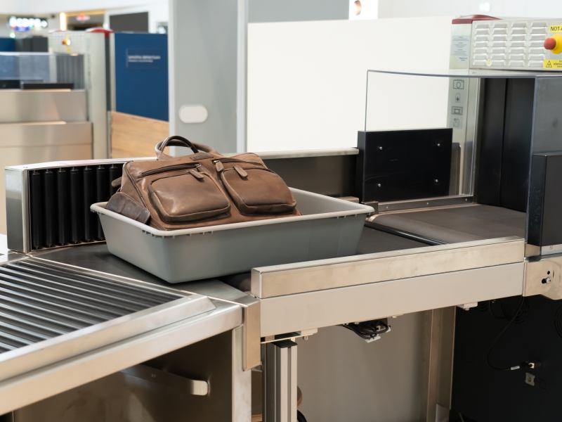 Gepäck in Transportwanne am Weg von Rollbahn in Röntgengerät (inklusive senkrechter Umlenkrollen)